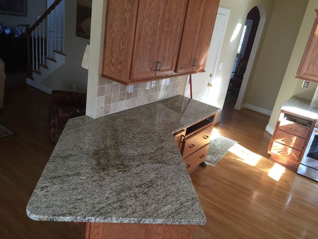 A kitchen with a granite counter top and wooden cabinets.