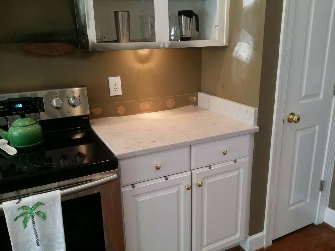 A kitchen with white cabinets and a stove top oven
