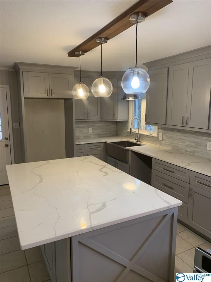 A kitchen with gray cabinets , white counter tops , and a large island.