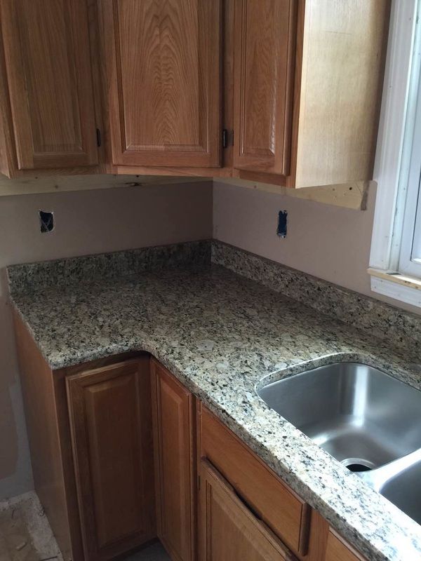 A kitchen with granite counter tops and a stainless steel sink.