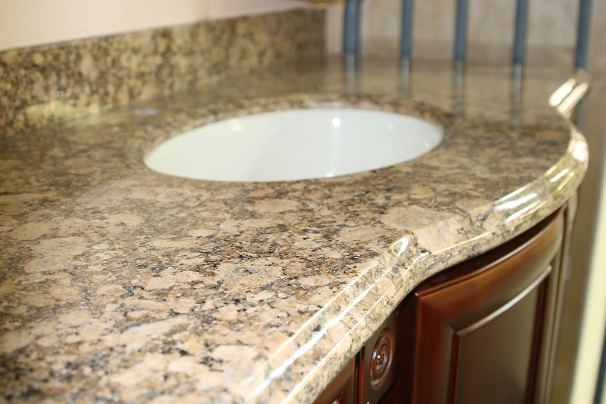 A bathroom vanity with a granite counter top and a sink.