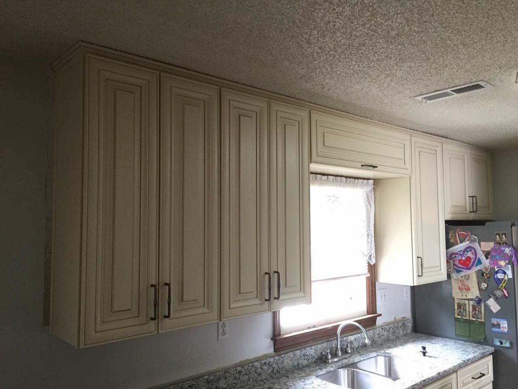 A kitchen with white cabinets , granite counter tops , a sink and a refrigerator.
