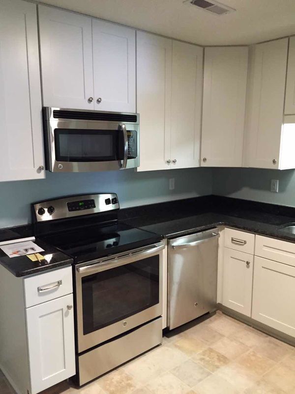 A kitchen with stainless steel appliances and white cabinets.