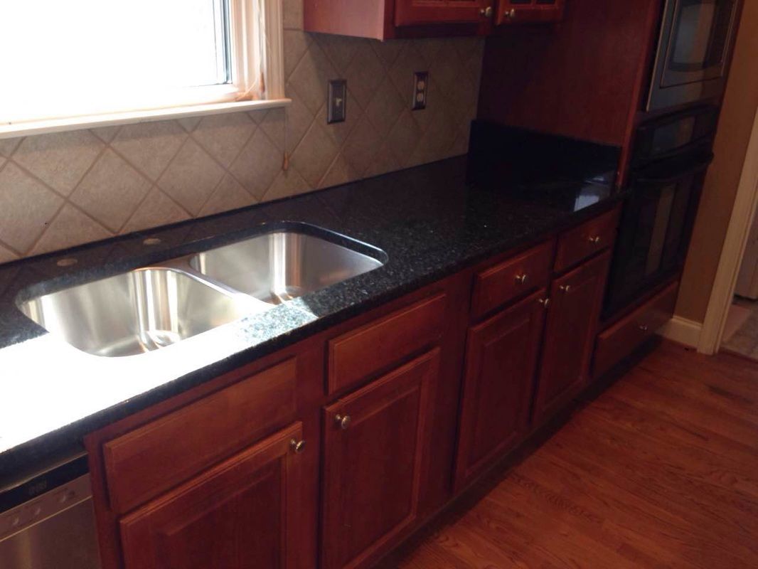 A kitchen with wooden cabinets and a stainless steel sink