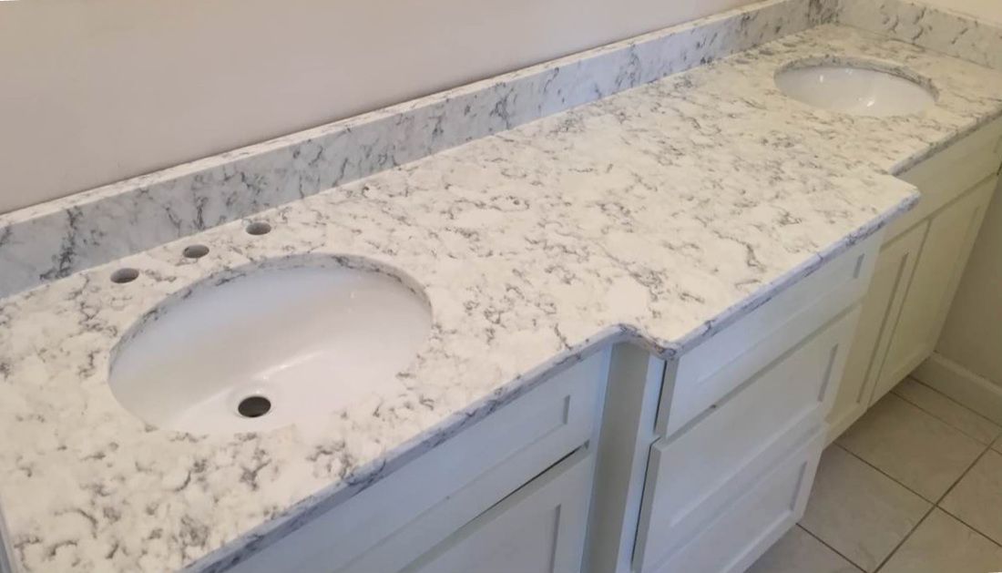 A bathroom with two sinks and a marble counter top.