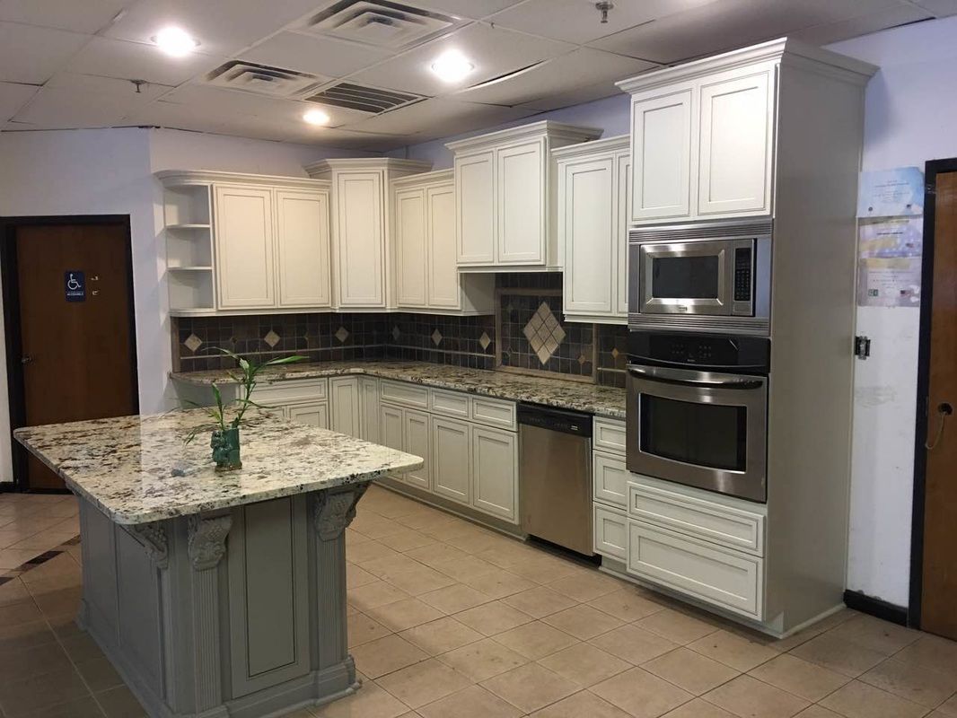 A kitchen with white cabinets , granite counter tops , stainless steel appliances and a large island.