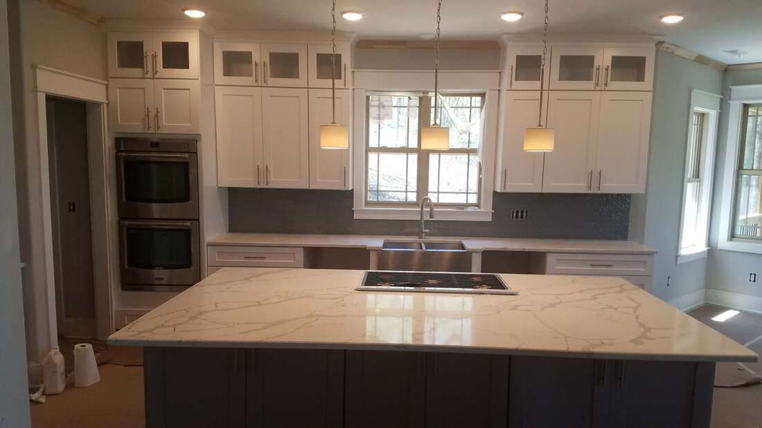 A kitchen with white cabinets and a large island in the middle.