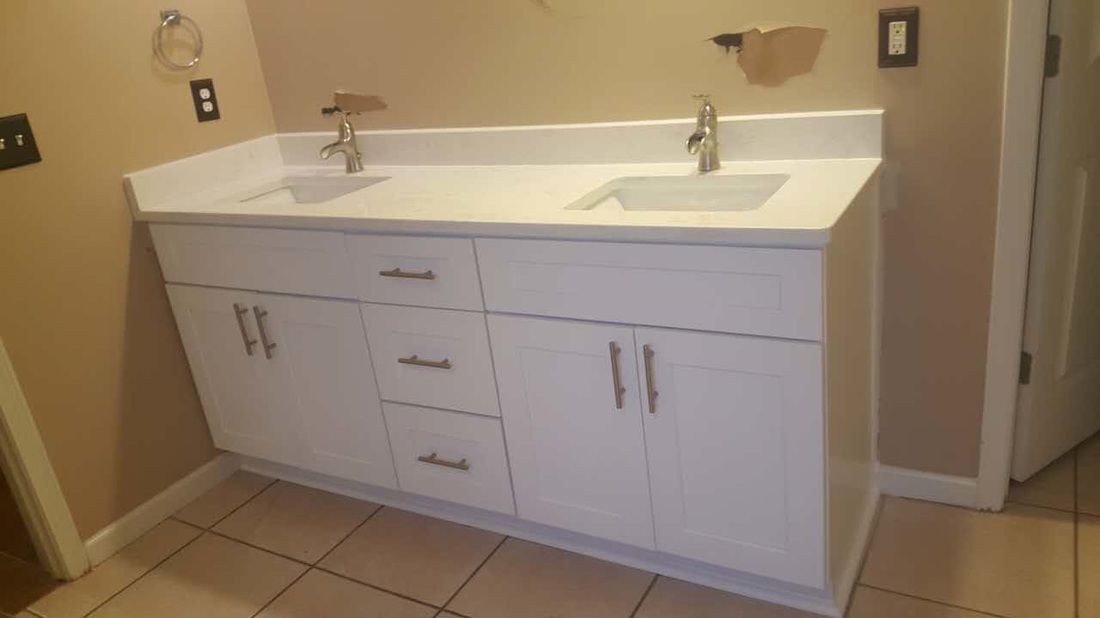 A bathroom with a double sink and white cabinets.