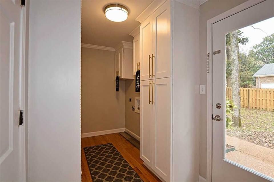A hallway in a house with white cabinets and a door.