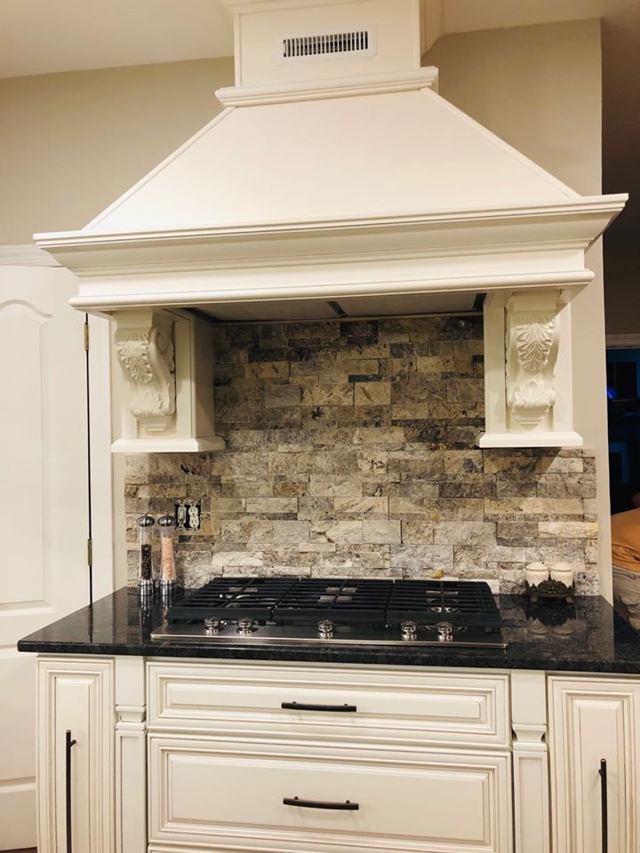A kitchen with a stove top oven and a hood above it.