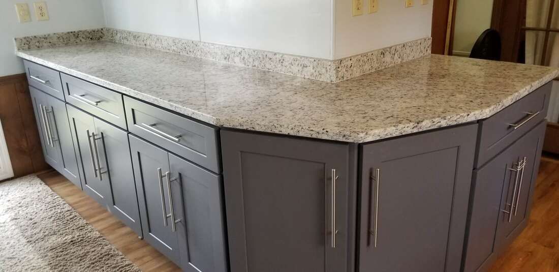 A kitchen with gray cabinets and a granite counter top.