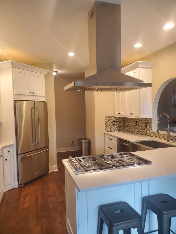 A kitchen with a stove top oven , refrigerator , sink and stools.