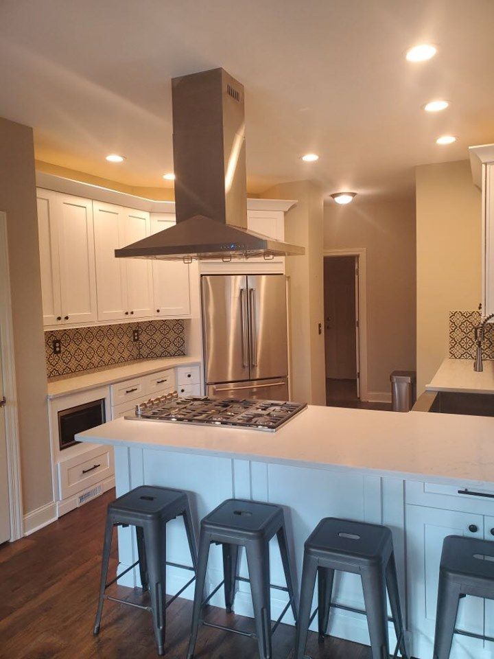 A kitchen with stools and a stove top oven.