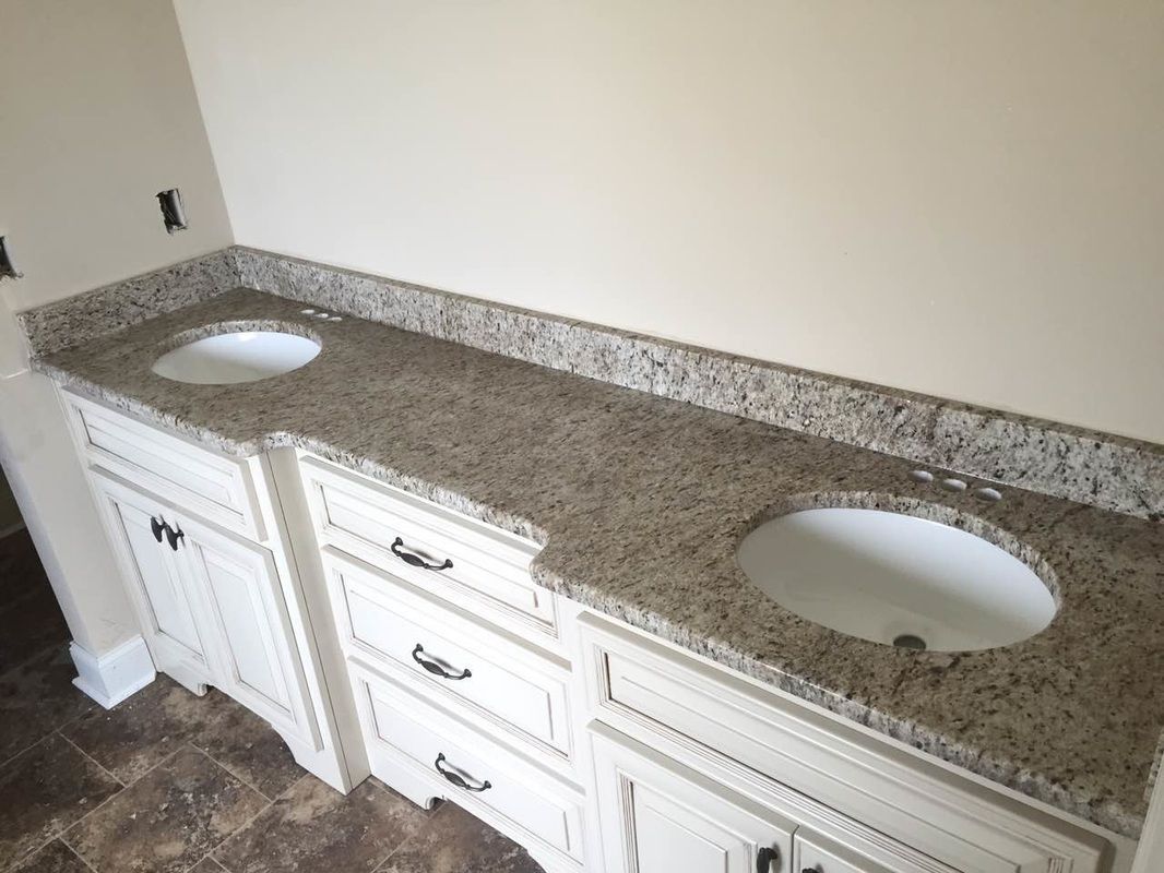 A bathroom with two sinks and granite counter tops.