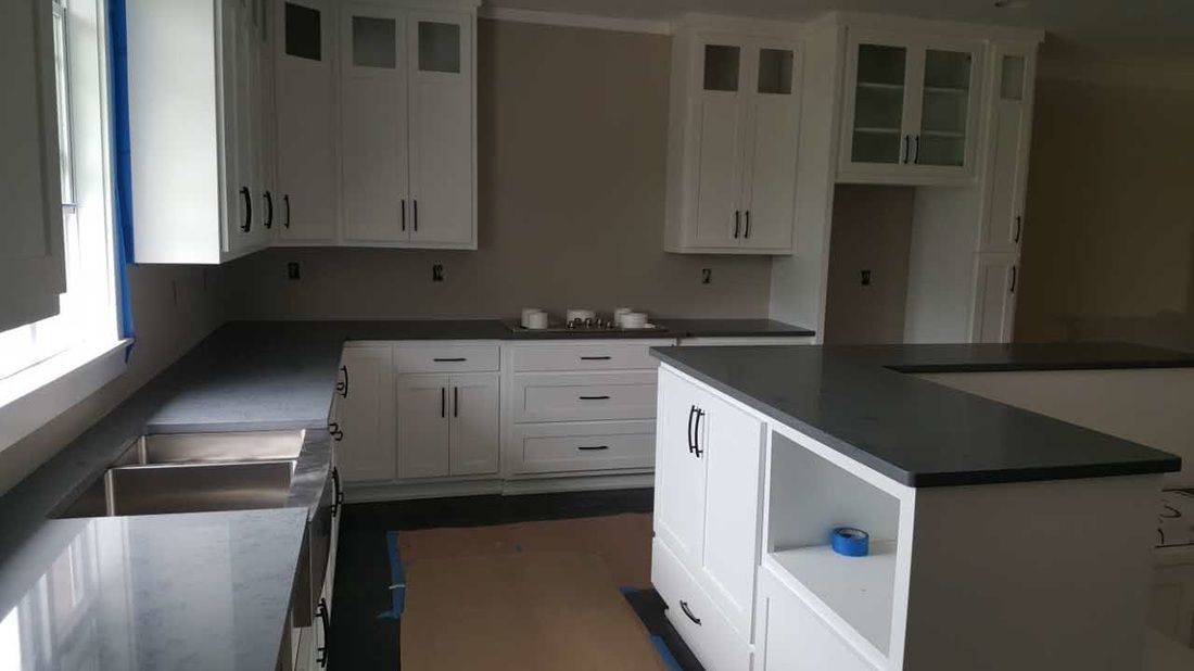 A kitchen with white cabinets and black counter tops is being remodeled.
