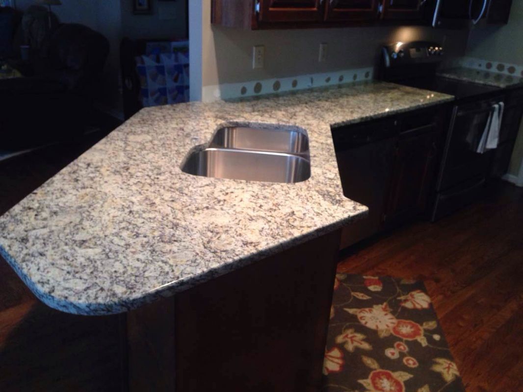A kitchen with granite counter tops and a stainless steel sink