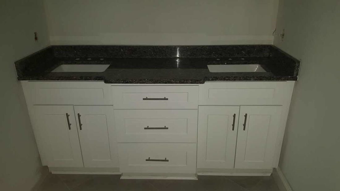 A bathroom vanity with two sinks and black granite counter tops.