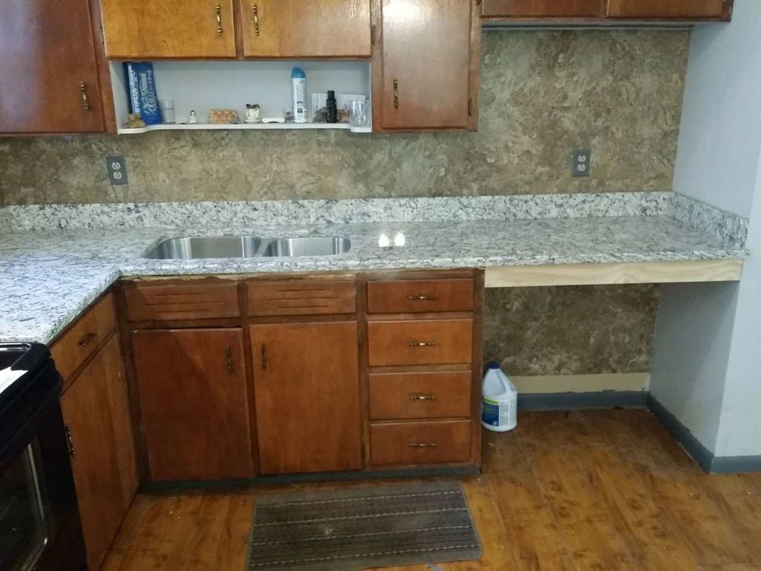 A kitchen with granite counter tops and wooden cabinets.