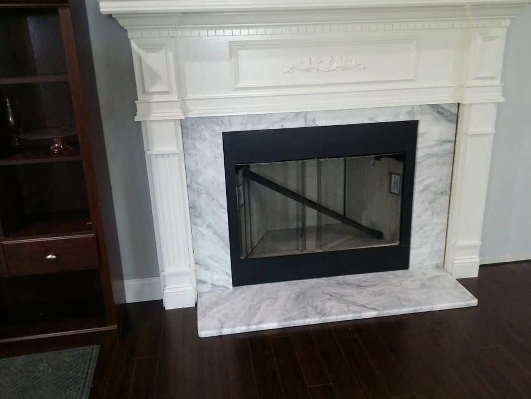 A white fireplace with a black door in a living room