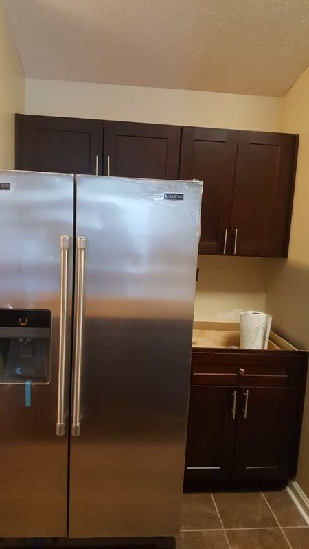 A stainless steel refrigerator is sitting in a kitchen next to a sink.