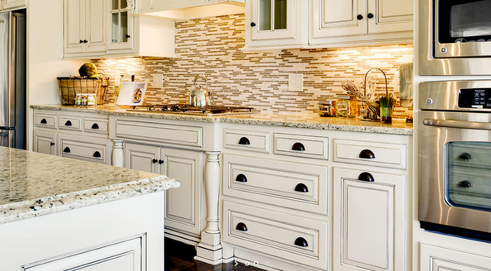 A kitchen with white cabinets , granite counter tops , and stainless steel appliances.