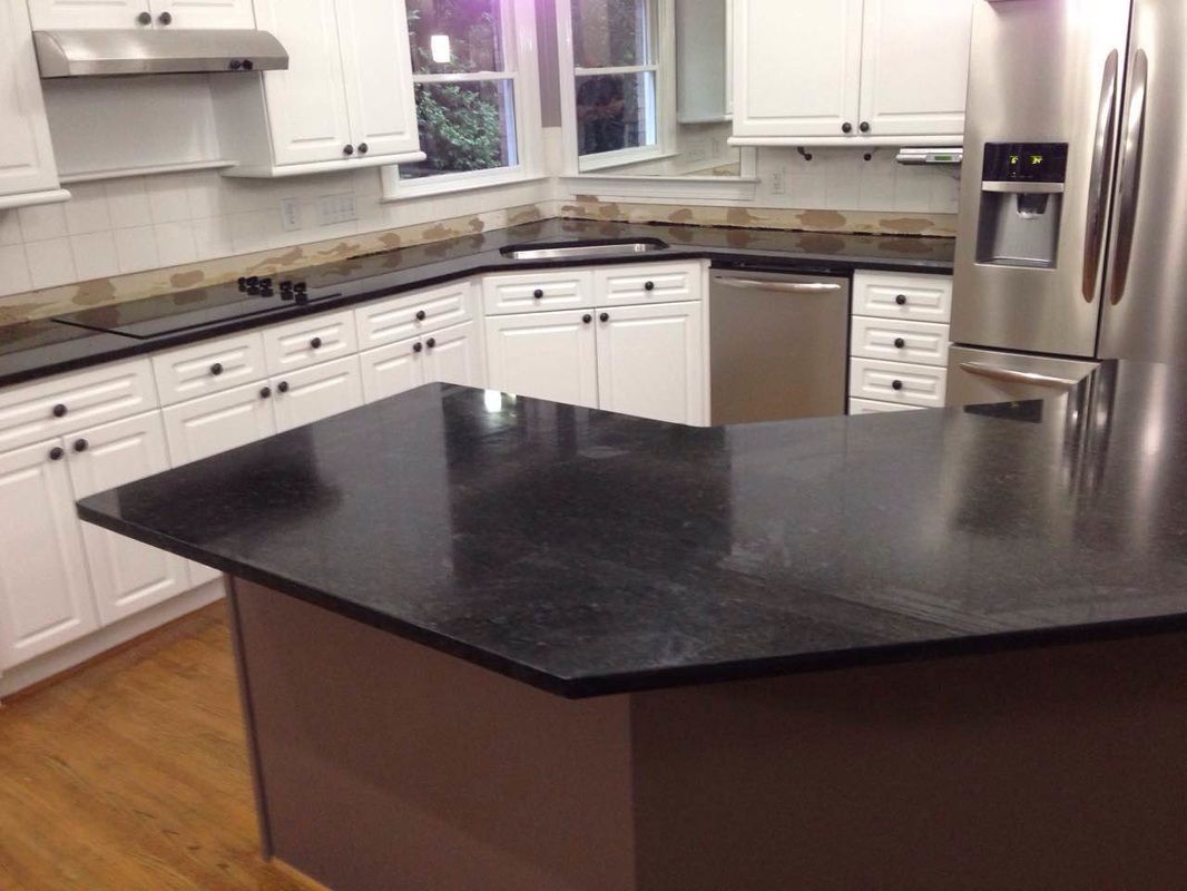 A kitchen with black counter tops and white cabinets