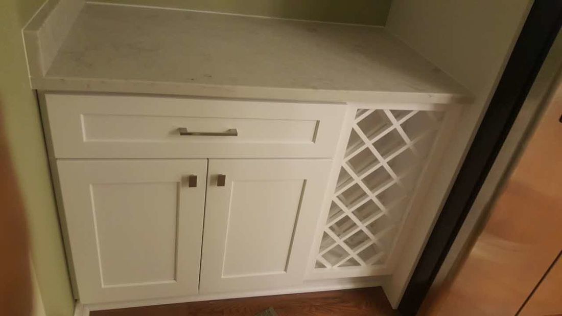 A white cabinet with a wine rack underneath it.