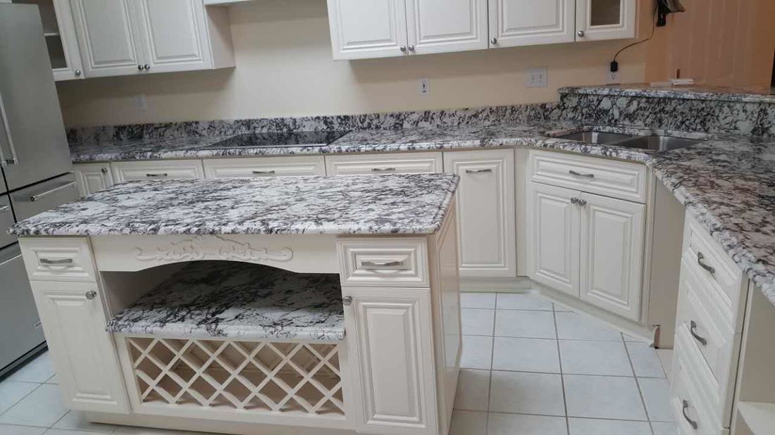 A kitchen with white cabinets and granite counter tops.