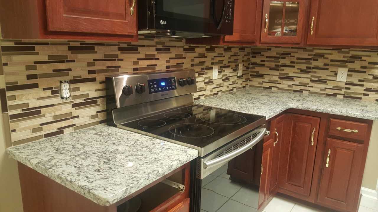 A kitchen with a stove , microwave , and granite counter tops.