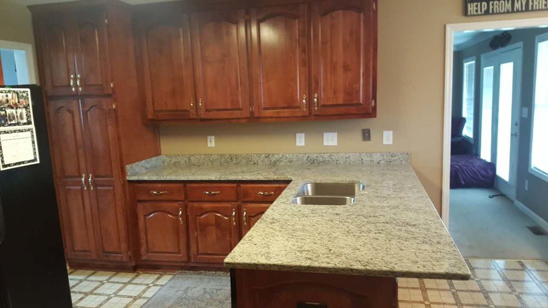 A kitchen with granite counter tops and wooden cabinets.