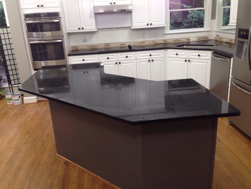 A kitchen with black granite counter tops and white cabinets