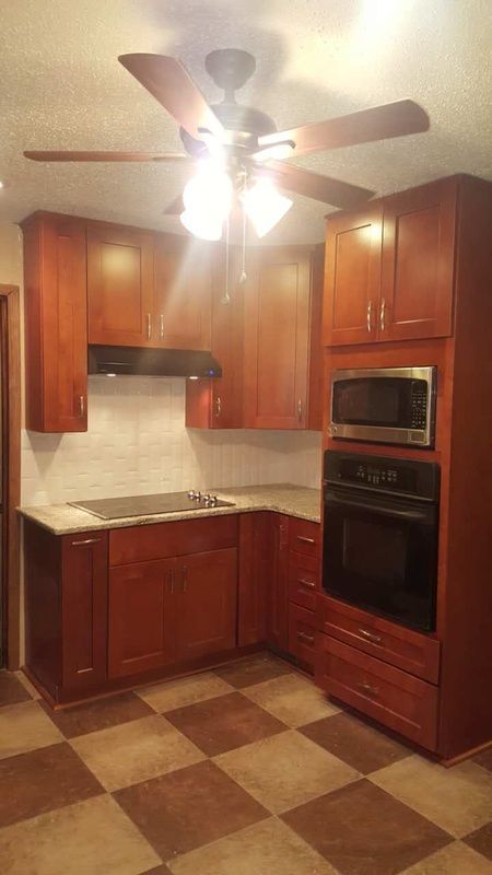 A kitchen with wooden cabinets , a microwave , and a ceiling fan.