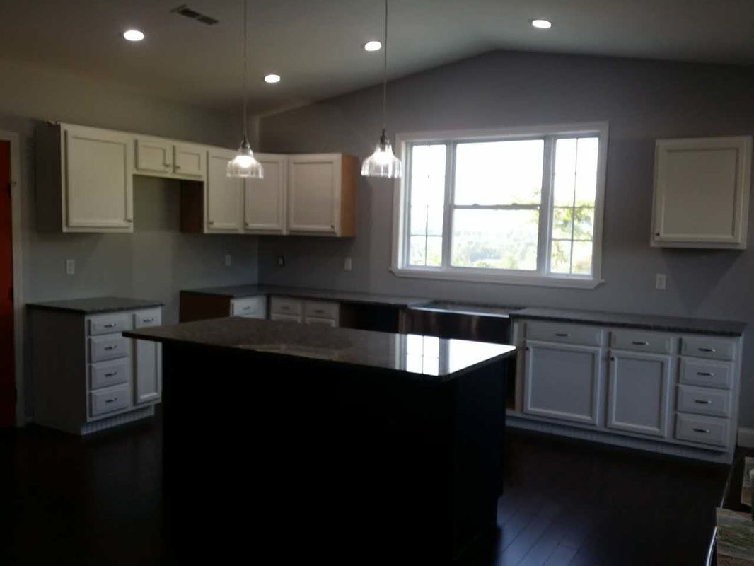 An empty kitchen with white cabinets and a large island