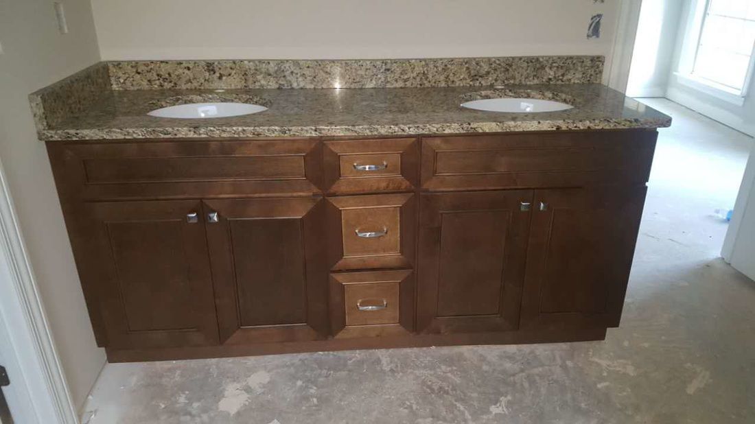 A bathroom vanity with two sinks and granite counter tops.