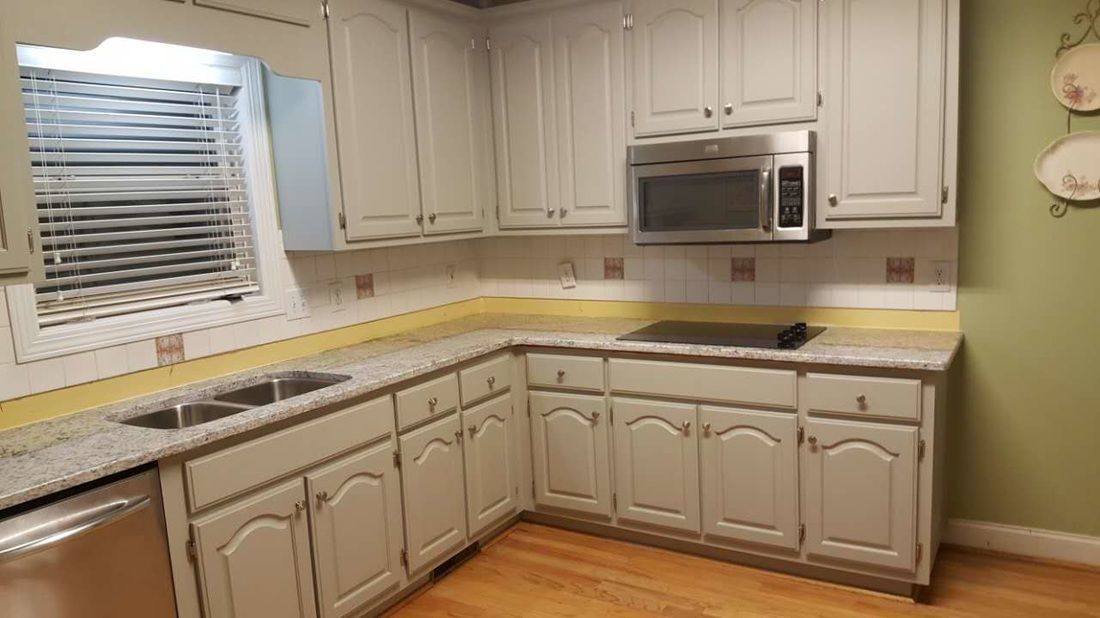 A kitchen with white cabinets , granite counter tops , stainless steel appliances and a window.