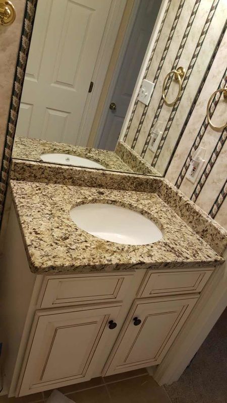 A bathroom sink with a granite counter top and a mirror.