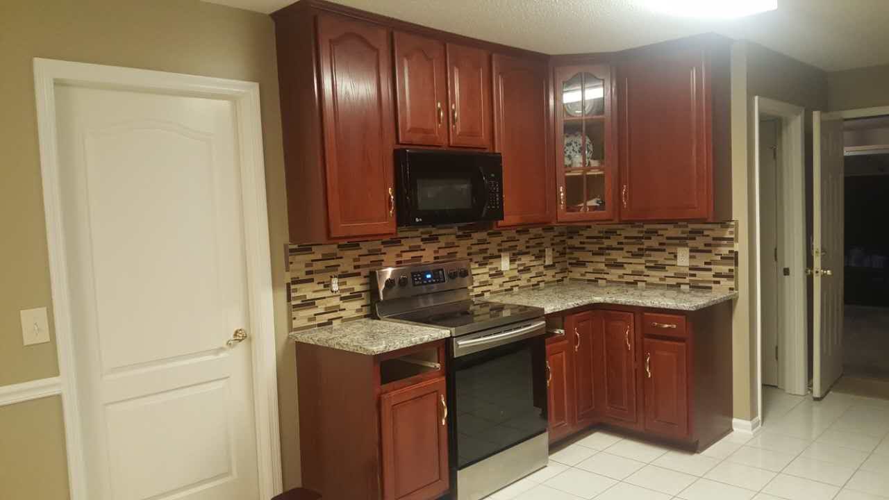 A kitchen with wooden cabinets , stainless steel appliances , and granite counter tops.