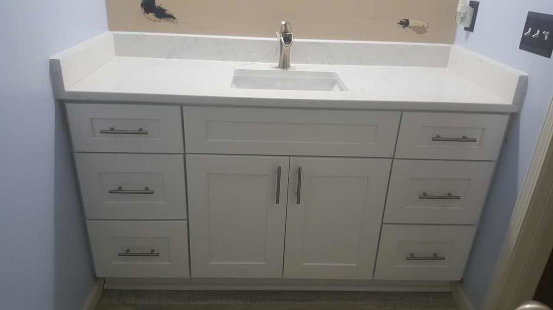 A bathroom vanity with a sink , drawers and cabinets.