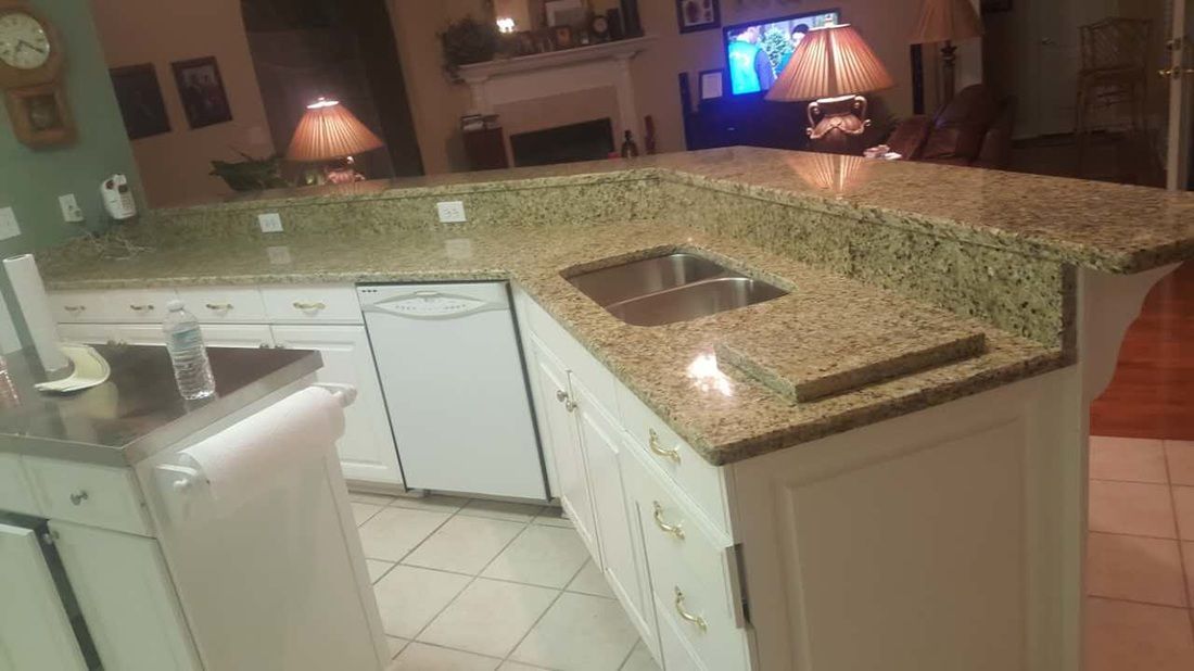 A kitchen with granite counter tops , white cabinets , and a sink.