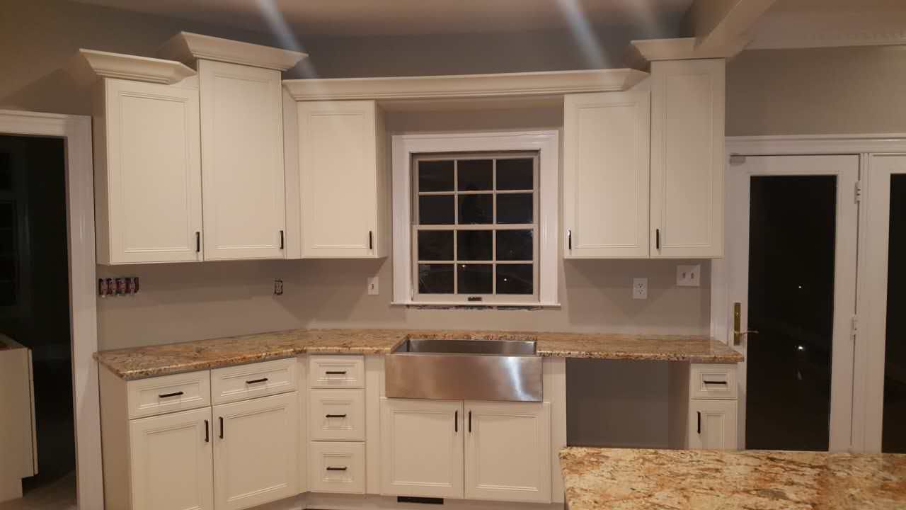 A kitchen with white cabinets and a stainless steel sink