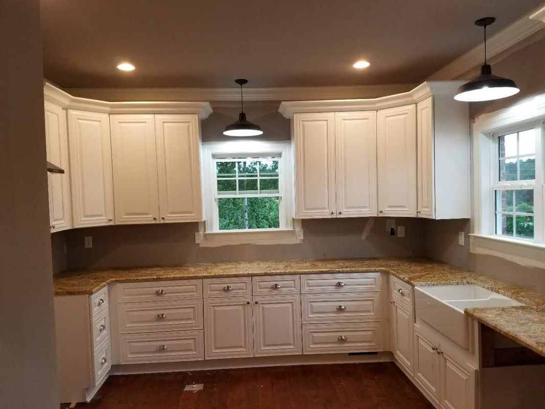 A kitchen with white cabinets , granite counter tops , and a sink.