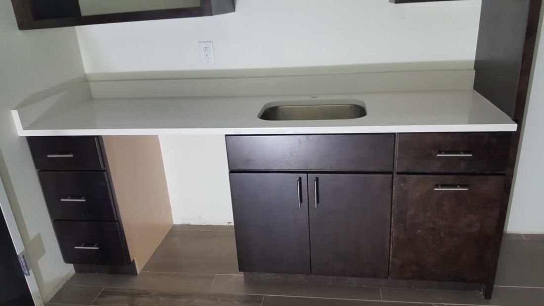 A kitchen with a sink , cabinets and drawers