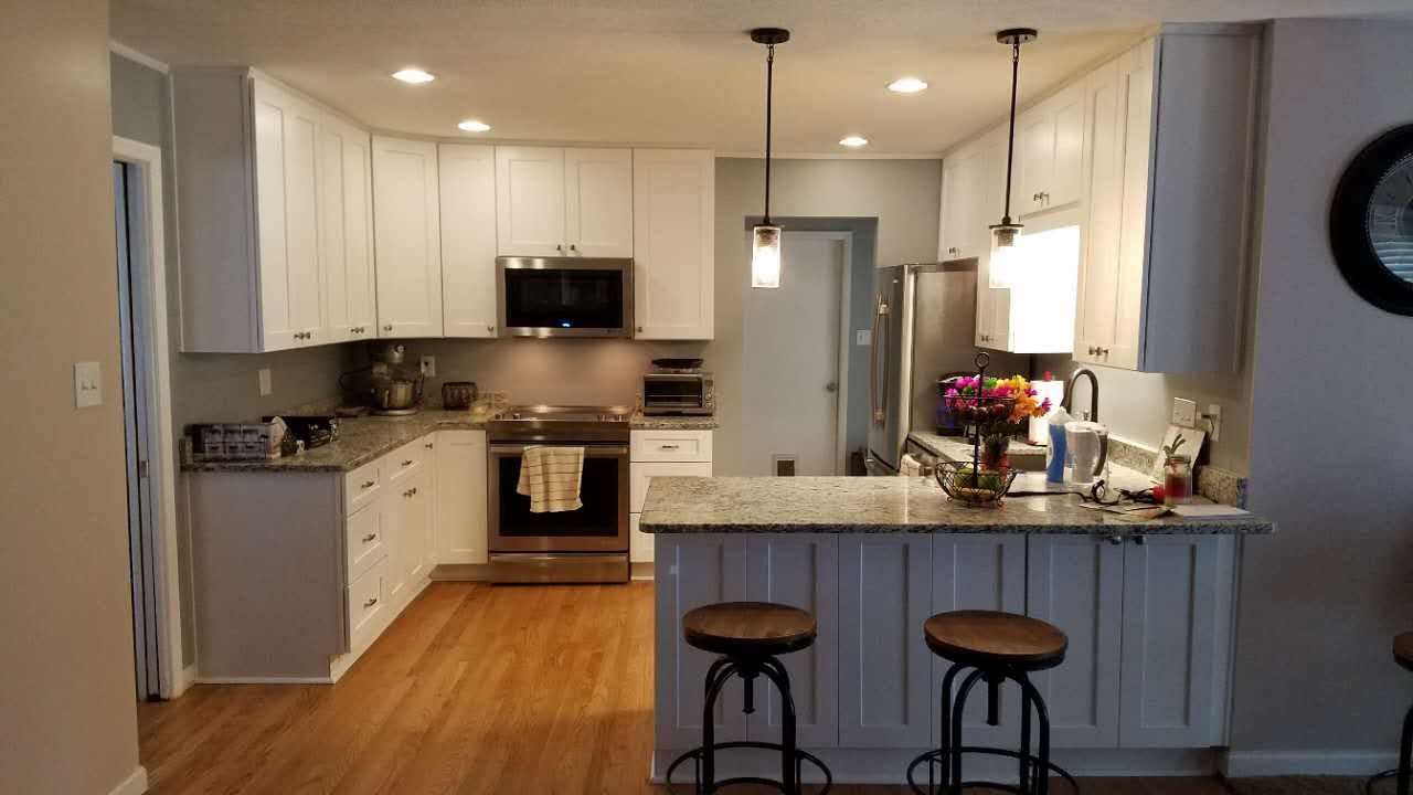 A kitchen with white cabinets , granite counter tops , stainless steel appliances and a large island.