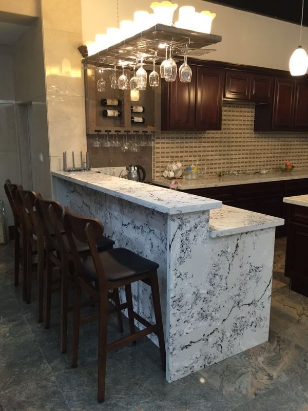 A kitchen with a bar and wine glasses hanging from the ceiling