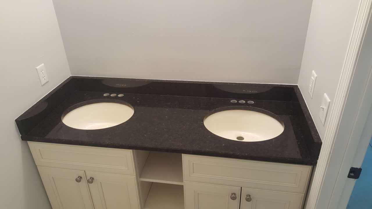 A bathroom with two sinks and a black counter top.