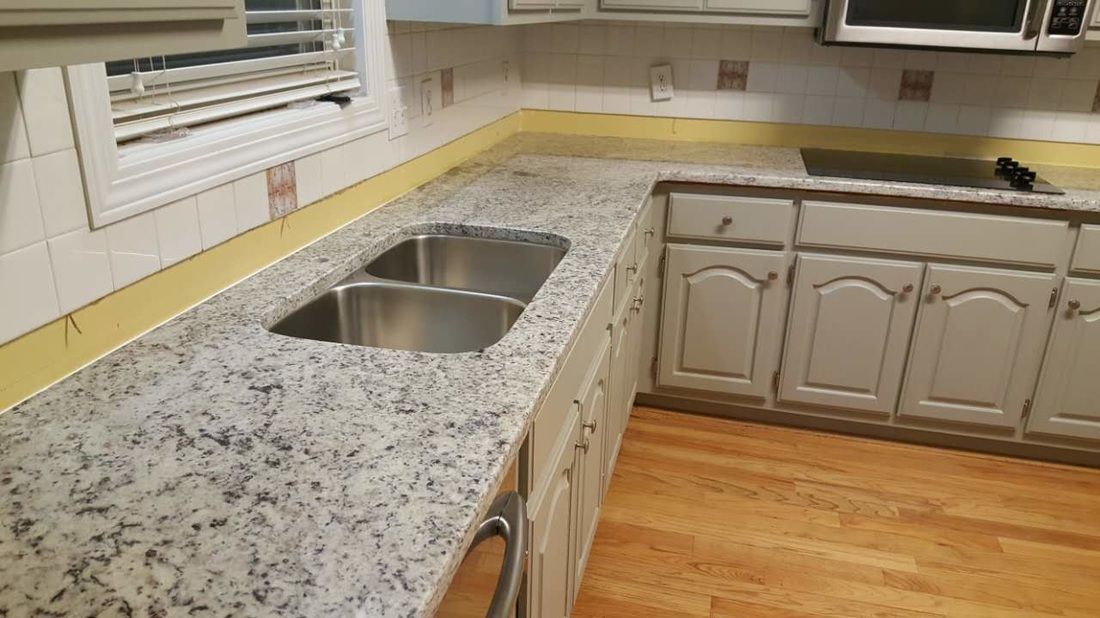 A kitchen with granite counter tops and stainless steel sinks.