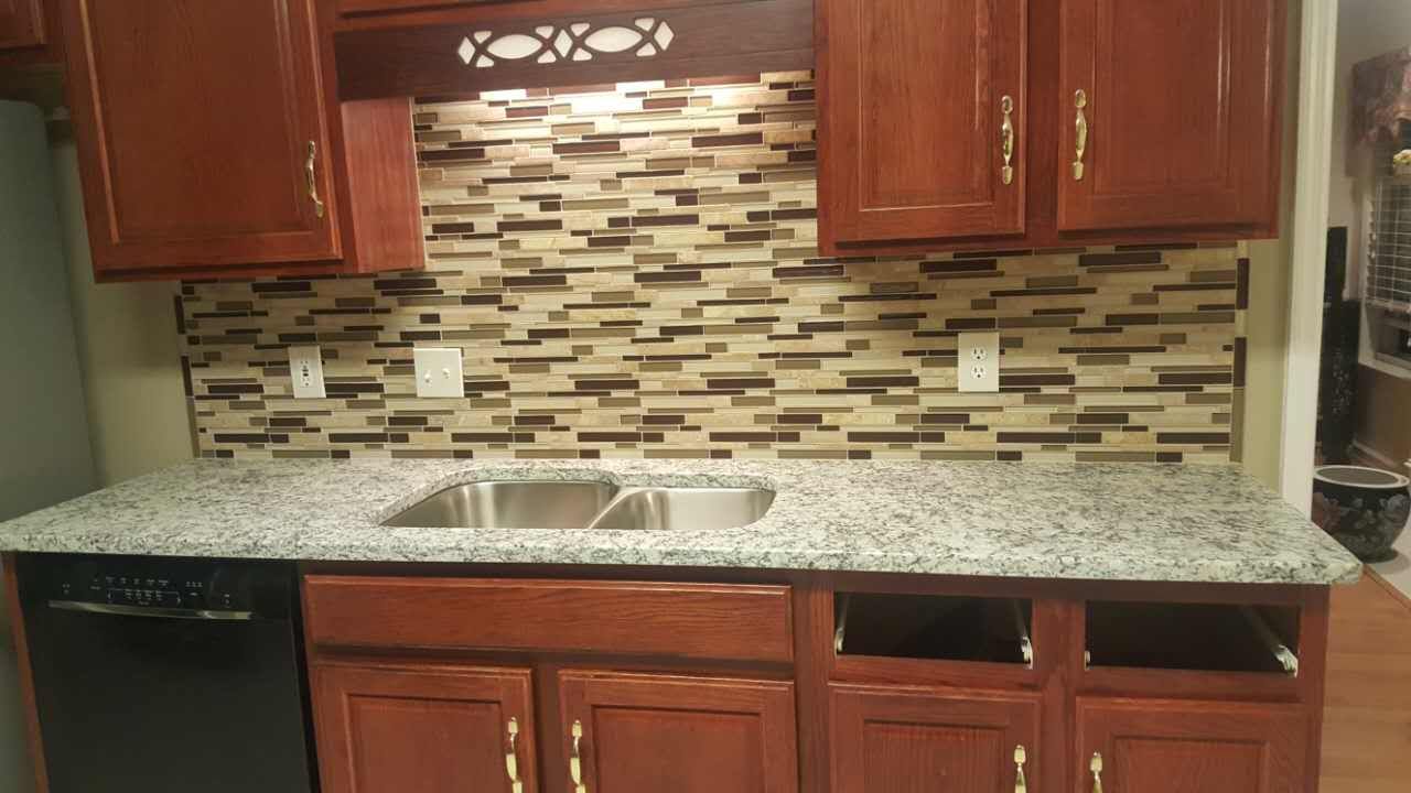 A kitchen with granite counter tops , stainless steel sink , and wooden cabinets.