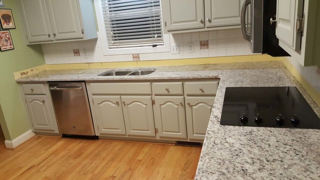 A kitchen with granite counter tops , white cabinets , stainless steel appliances and a stove.