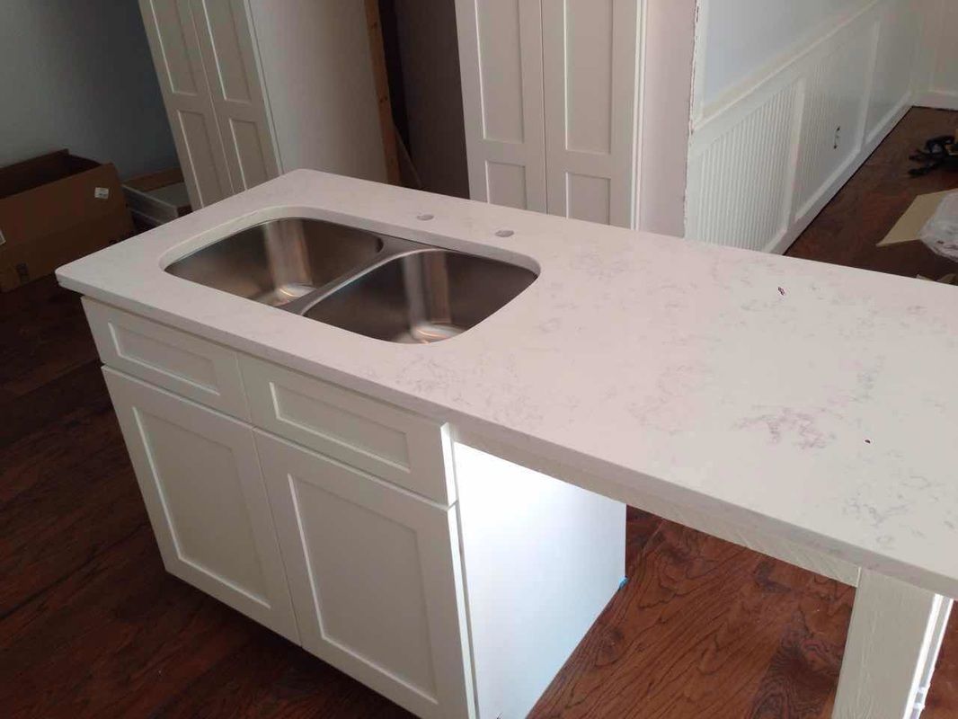 A stainless steel sink is sitting on top of a white counter.