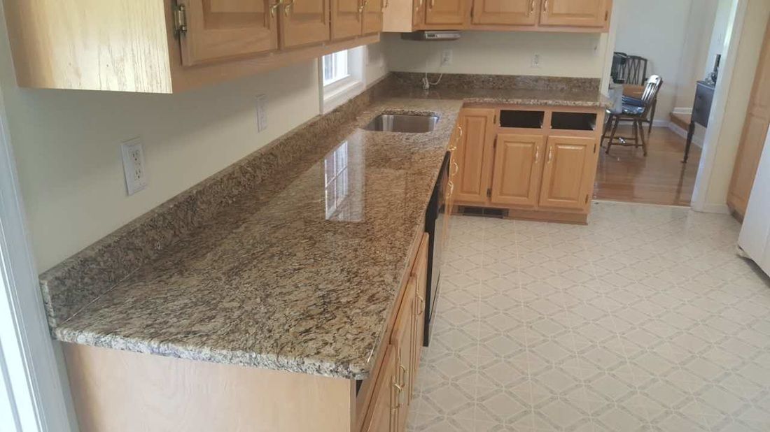 A kitchen with granite counter tops and wooden cabinets.